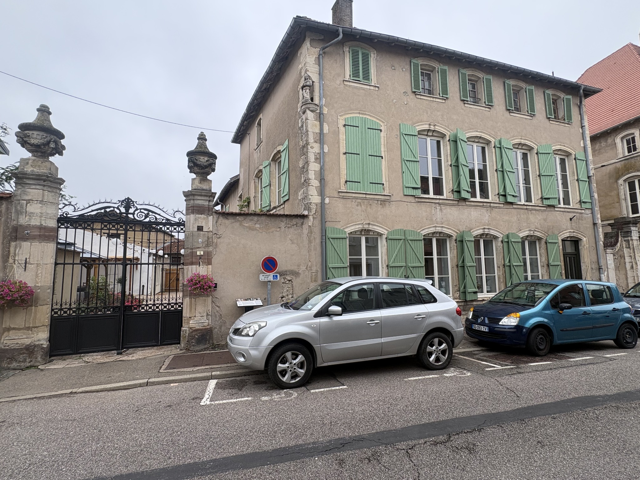 La façade de la villa avec ses volets verts, la statue d’angle et le portail depuis la rue