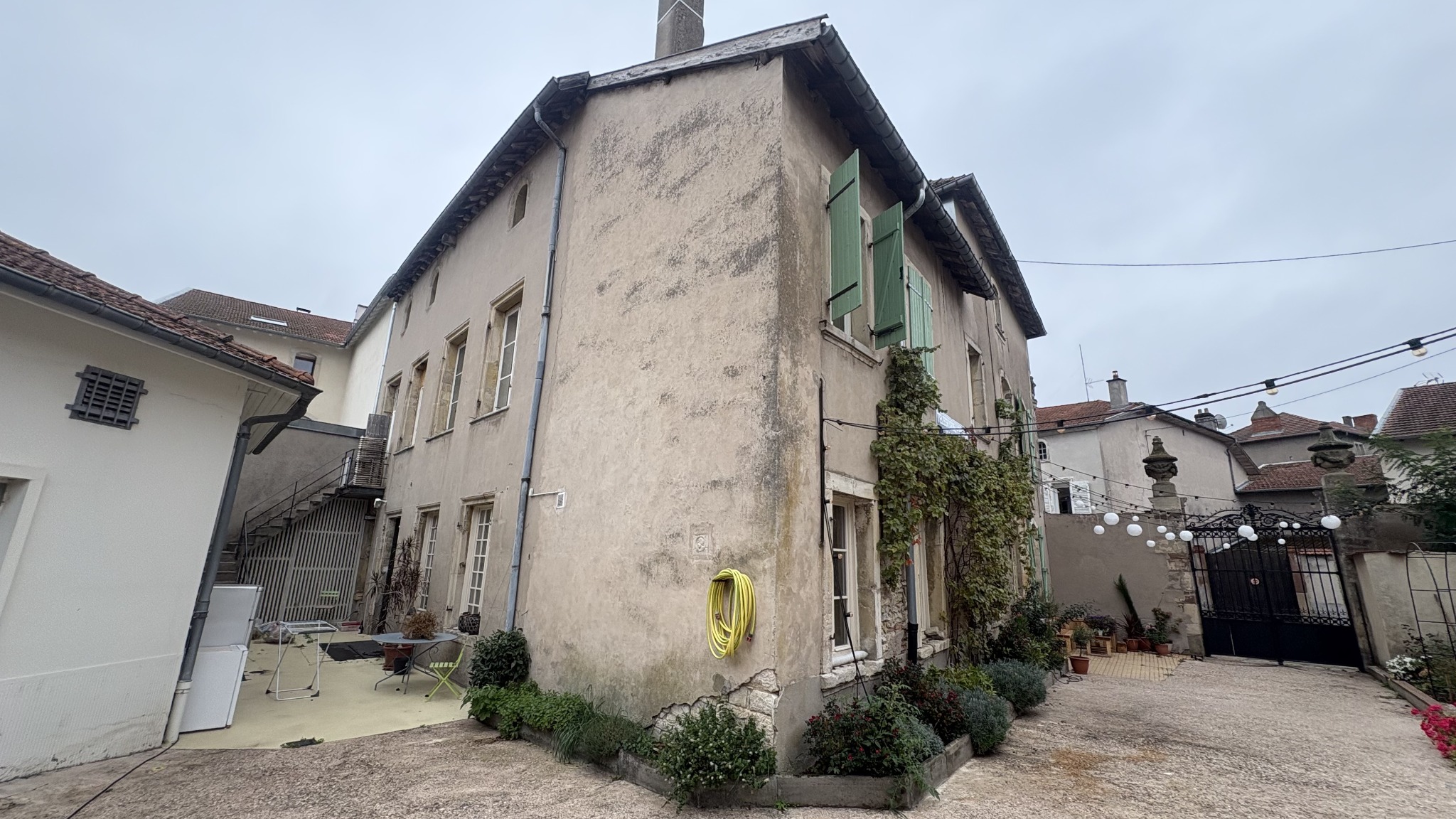 Vue latérale de la maison depuis la cour avec son escalier extérieur et le portail