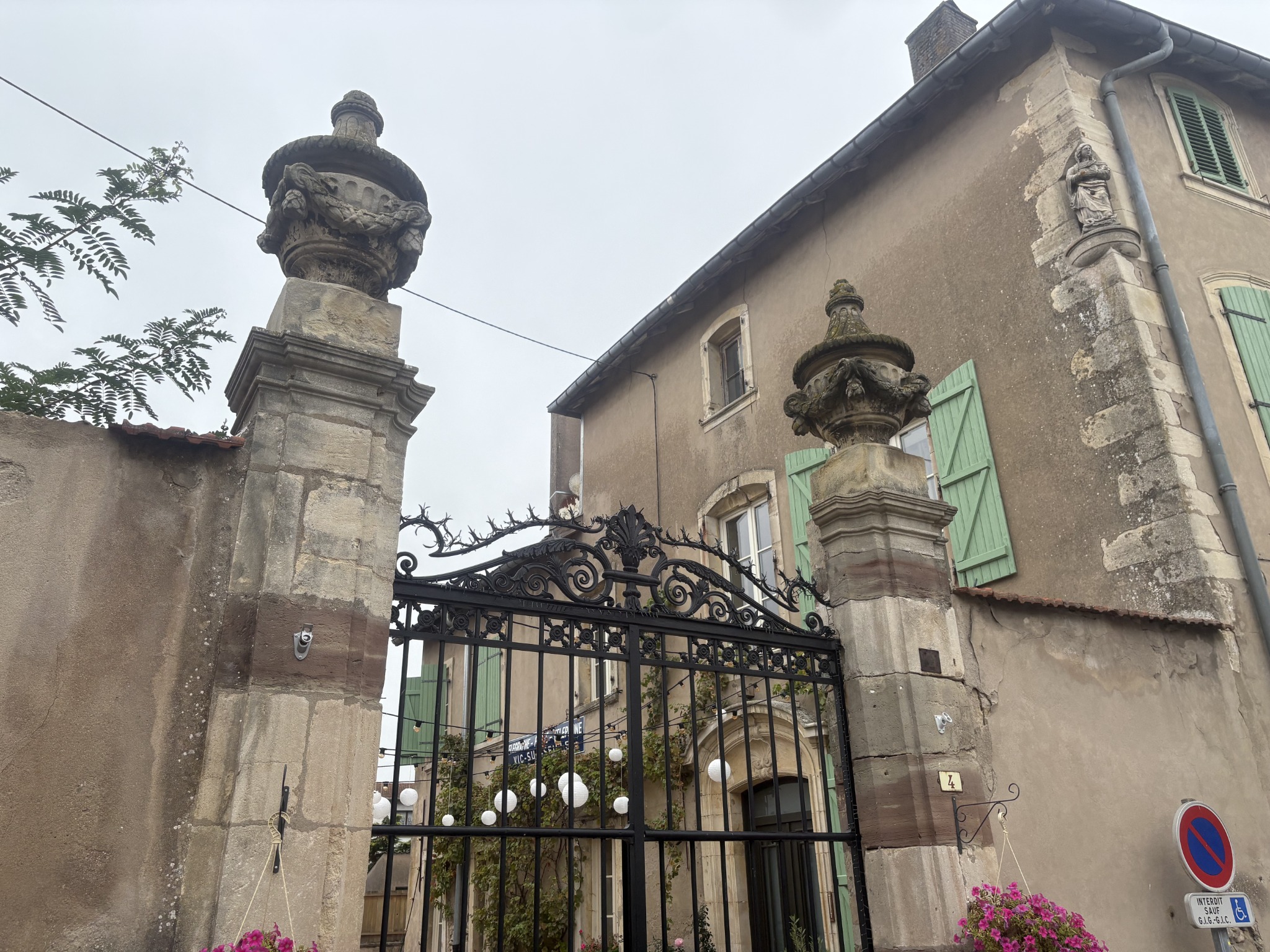 Les deux piliers ornés du portail, les décors métalliques et la statue d’angle de la maison